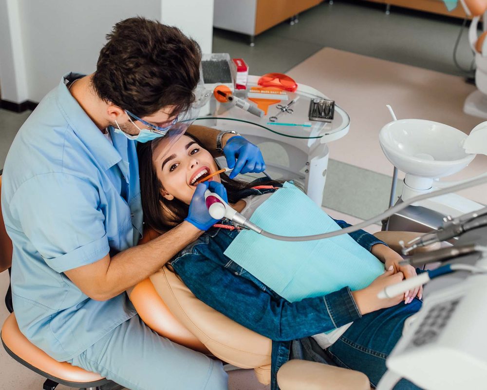 Young female patient with open mouth examining dental inspection at dentist office.