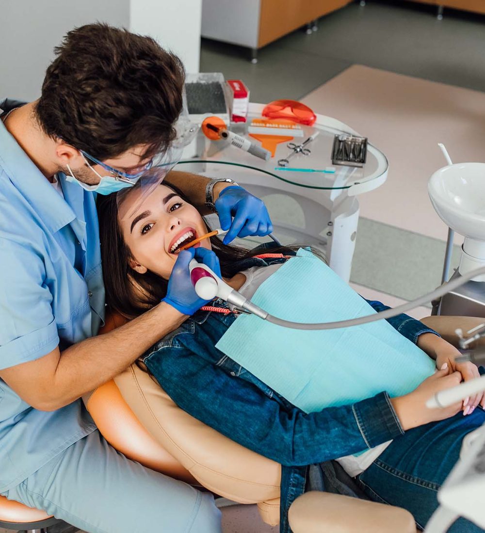 Young female patient with open mouth examining dental inspection at dentist office.